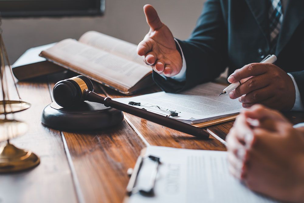 Zwei Männer besprechen verschiedene Dinge und Blicken dabei in Bücher und Unterlagen